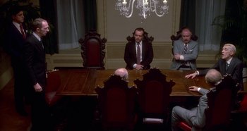 Movie still from “Prizzi's Honor” (1985), directed by John Huston – A group of people sitting at a table in front of a chandelier; Wide shot, High angle