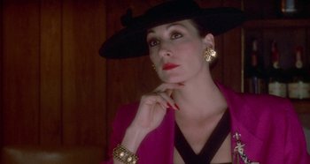 Movie still from “Prizzi's Honor” (1985), directed by John Huston – A woman wearing a black hat and a pink jacket; Close Up shot, Low angle