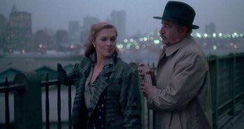 Movie still from “Prizzi's Honor” (1985), directed by John Huston – A man and a woman standing next to each other on a bridge; Medium shot, Over the shoulder angle