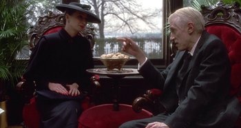 Movie still from “Prizzi's Honor” (1985), directed by John Huston – A man and a woman sitting at a table with a bowl of food; Medium shot, Over the shoulder angle