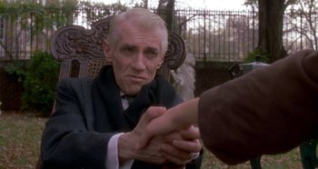 Movie still from “Prizzi's Honor” (1985), directed by John Huston – An older man sitting in a chair shaking hands with a younger man; Close Up shot, Over the shoulder angle