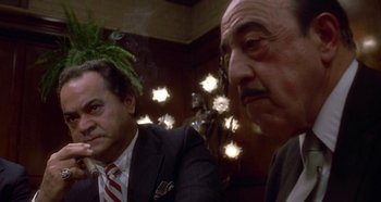 Movie still from “Prizzi's Honor” (1985), directed by John Huston – Two men in suits sitting next to each other in a room; Close Up shot, Low angle