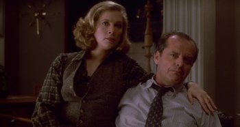 Movie still from “Prizzi's Honor” (1985), directed by John Huston – A man and a woman sitting next to each other; Medium shot, Low angle