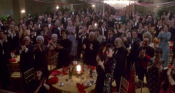 Movie still from “Prizzi's Honor” (1985), directed by John Huston – A group of people sitting around a table with a cake; Wide shot, High angle