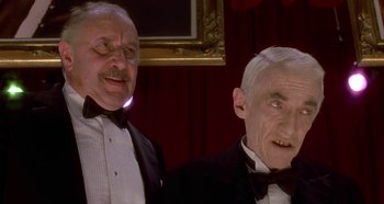 Movie still from “Prizzi's Honor” (1985), directed by John Huston – Two older men in tuxedos are standing next to each other; Medium shot, Low angle