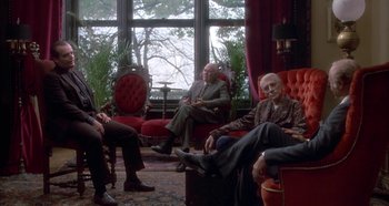 Movie still from “Prizzi's Honor” (1985), directed by John Huston – A group of people sitting in a room with a large window; Wide shot, High angle