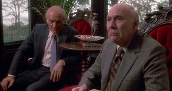 Movie still from “Prizzi's Honor” (1985), directed by John Huston – Two men in business suits sitting in front of each other; Medium shot, Low angle