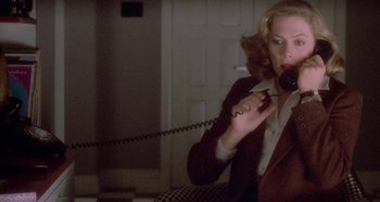 Movie still from “Prizzi's Honor” (1985), directed by John Huston – A woman talking on a phone while sitting in a chair; Medium shot, High angle