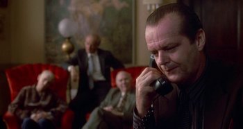 Movie still from “Prizzi's Honor” (1985), directed by John Huston – A man talking on a phone while sitting in a room; Medium shot, Over the shoulder angle