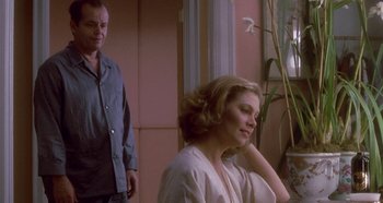 Movie still from “Prizzi's Honor” (1985), directed by John Huston – A man and a woman standing next to each other in a room; Medium shot, Over the shoulder angle