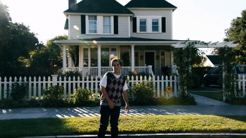 Movie still from “Project X” (2012), directed by Nima Nourizadeh – A man standing on the side of a road in front of a house; Wide shot, Low angle