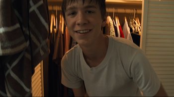 Movie still from “Project X” (2012), directed by Nima Nourizadeh – A young man smiling in front of a row of clothes; Close Up shot, Low angle