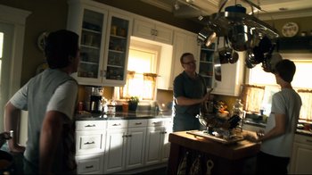 Movie still from “Project X” (2012), directed by Nima Nourizadeh – A woman in a kitchen with a pot on a stove; Medium shot, Over the shoulder angle
