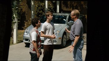 Movie still from “Project X” (2012), directed by Nima Nourizadeh – Three young men standing in front of a silver car; Wide shot, Over the shoulder angle