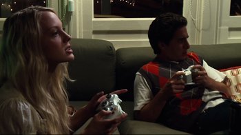 Movie still from “Project X” (2012), directed by Nima Nourizadeh – A man and a woman sitting on a couch holding game controllers; Medium shot, High angle