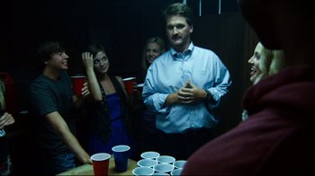Movie still from “Project X” (2012), directed by Nima Nourizadeh – A group of people standing around a table with cups on top of it; Medium shot, Over the shoulder angle