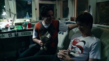Movie still from “Project X” (2012), directed by Nima Nourizadeh – Two young men sitting on a couch and one is holding a trophy; Medium shot, Over the shoulder angle