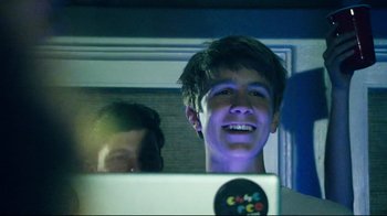 Movie still from “Project X” (2012), directed by Nima Nourizadeh – A young man smiles while looking at a computer screen; Close Up shot, Over the shoulder angle