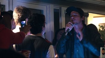 Movie still from “Project X” (2012), directed by Nima Nourizadeh – A group of people standing in a room with microphones; Medium shot, Over the shoulder angle