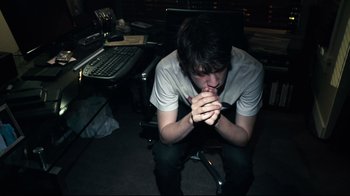 Movie still from “Project X” (2012), directed by Nima Nourizadeh – A man sitting on a chair in front of a computer keyboard; Medium shot, High angle