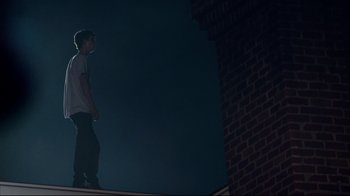 Movie still from “Project X” (2012), directed by Nima Nourizadeh – A person standing on the side of a brick building at night; Wide shot, Low angle