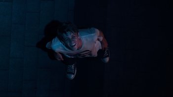 Movie still from “Project X” (2012), directed by Nima Nourizadeh – A young boy standing in a dark room laughing; Medium shot, Overhead angle