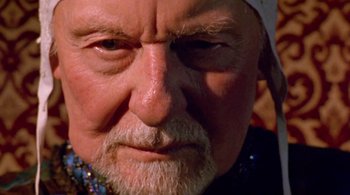 Movie still from “Prospero's Books” (1991), directed by Peter Greenaway – An old man with a white beard wearing a white hat; Extreme Close Up shot, Over the shoulder angle