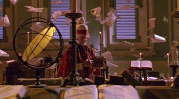 Movie still from “Prospero's Books” (1991), directed by Peter Greenaway – An old man is standing in front of some papers; Medium shot, Low angle