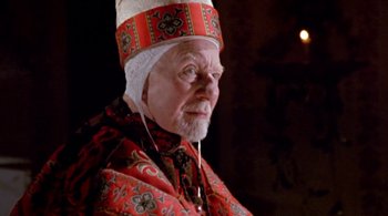 Movie still from “Prospero's Books” (1991), directed by Peter Greenaway – An older man wearing a red and white headpiece; Close Up shot, High angle