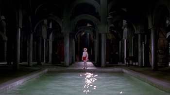 Movie still from “Prospero's Books” (1991), directed by Peter Greenaway – A woman standing in a pool of water in an indoor setting; Extreme Wide shot, High angle