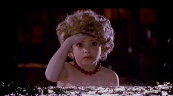 Movie still from “Prospero's Books” (1991), directed by Peter Greenaway – A young child with a red necklace in a dark room; Close Up shot, High angle