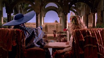 Movie still from “Prospero's Books” (1991), directed by Peter Greenaway – Two people sitting on a couch in a room; Wide shot, Low angle