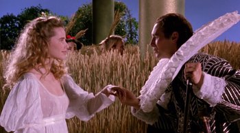 Movie still from “Prospero's Books” (1991), directed by Peter Greenaway – A man and a woman holding hands in front of a field; Medium shot, Low angle