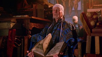 An older man holding an open book in a room