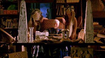 Movie still from “Prospero's Books” (1991), directed by Peter Greenaway – A man sitting at a table in a room with two women; Wide shot, High angle