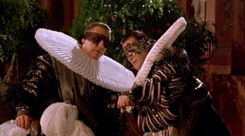 Movie still from “Prospero's Books” (1991), directed by Peter Greenaway – Two men dressed up in costumes and one is holding an umbrella and the other is wearing a mask; Medium shot, Low angle