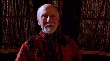 Movie still from “Prospero's Books” (1991), directed by Peter Greenaway – An older man wearing a red and black shirt; Medium shot, Overhead angle