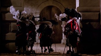 Movie still from “Prospero's Books” (1991), directed by Peter Greenaway – A group of people standing in front of an archway; Wide shot, Low angle