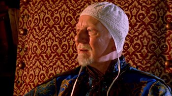 Movie still from “Prospero's Books” (1991), directed by Peter Greenaway – An older man wearing a white hat and listening to music; Close Up shot, High angle