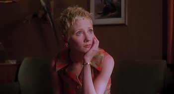 Movie still from “Psycho” (1998), directed by Gus Van Sant – A woman with short blonde spiky hair is sitting with her hand under her chin; Close Up shot, High angle