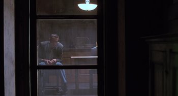 Movie still from “Psycho” (1998), directed by Gus Van Sant – A man sitting on a chair in front of a window; Wide shot, Low angle