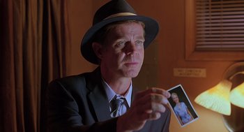 Movie still from “Psycho” (1998), directed by Gus Van Sant – A man in a suit and hat holding a picture; Close Up shot, Over the shoulder angle