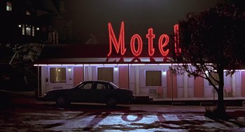 Movie still from “Psycho” (1998), directed by Gus Van Sant – A car parked in front of a motel lit up at night; Wide shot, Low angle