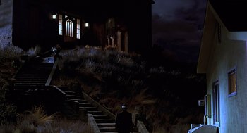 Movie still from “Psycho” (1998), directed by Gus Van Sant – A man standing on some steps in front of a house; Extreme Wide shot, Low angle