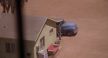 Movie still from “Psycho” (1998), directed by Gus Van Sant – An aerial view of a man standing next to an old truck; Extreme Wide shot, High angle