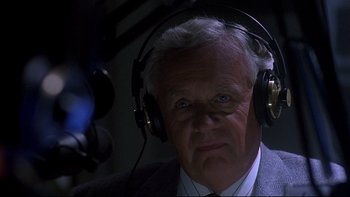 Movie still from “Psycho IV: The Beginning” (1990), directed by Mick Garris – An older man wearing headphones while sitting in a chair; Close Up shot, Low angle