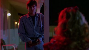 Movie still from “Psycho IV: The Beginning” (1990), directed by Mick Garris – A young man holding a camera in a dark room; Medium shot, Over the shoulder angle