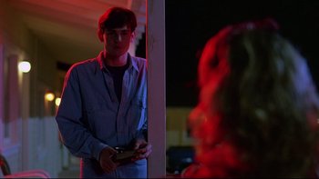 Movie still from “Psycho IV: The Beginning” (1990), directed by Mick Garris – A man standing next to a woman in a dark room; Medium shot, Over the shoulder angle