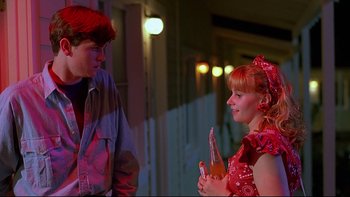 Movie still from “Psycho IV: The Beginning” (1990), directed by Mick Garris – A young man standing next to a young woman holding an object; Medium shot, Over the shoulder angle