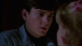 Movie still from “Psycho IV: The Beginning” (1990), directed by Mick Garris – A young man looking at the camera in the dark; Close Up shot, Over the shoulder angle